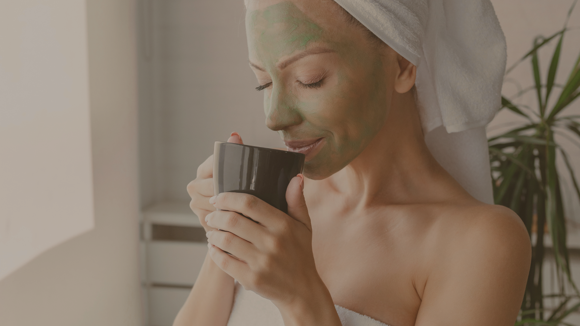Relaxed woman with green face mask, sipping a warm drink.