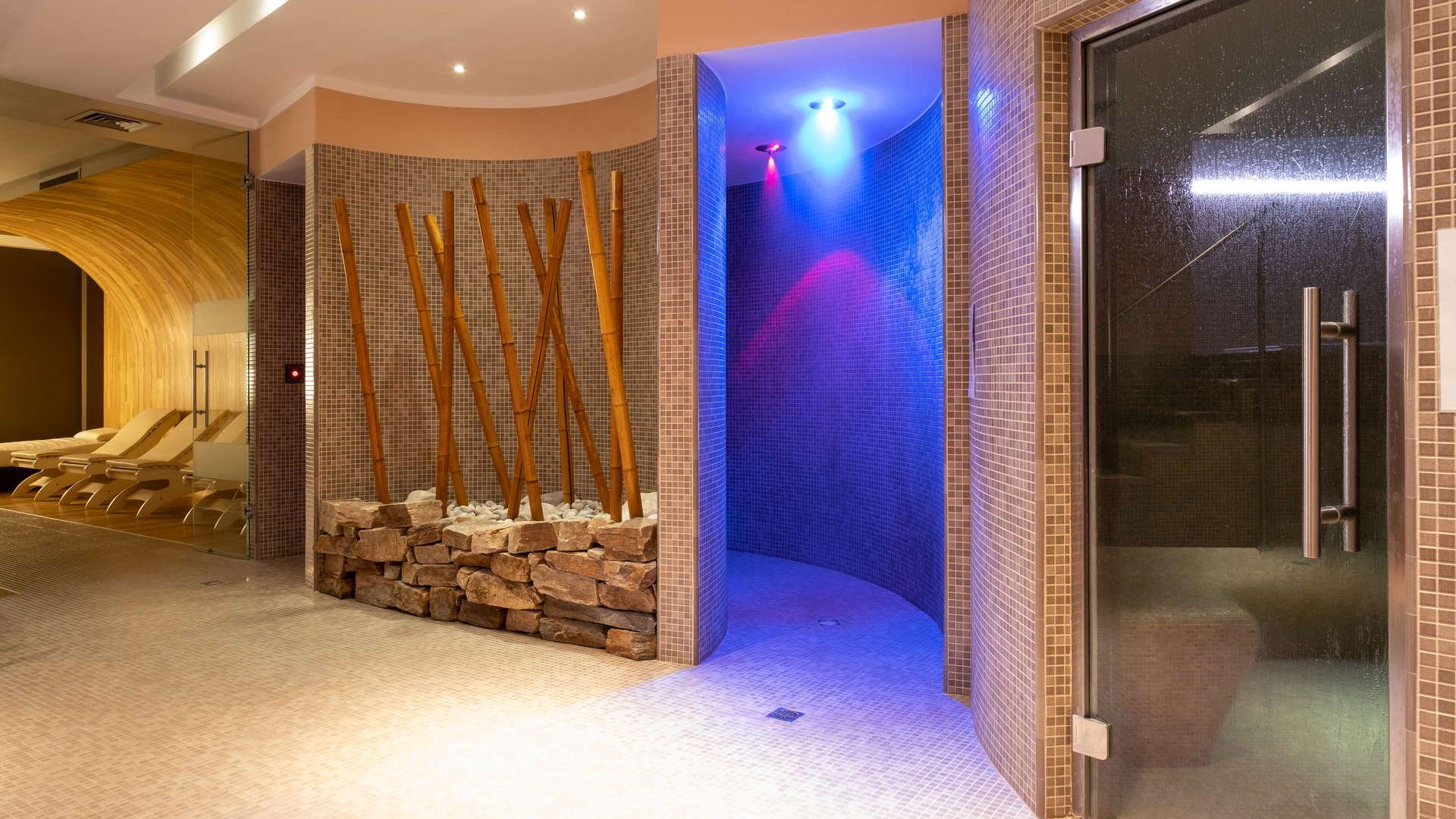 Area spa con docce colorate, sauna e decorazioni in bambù.