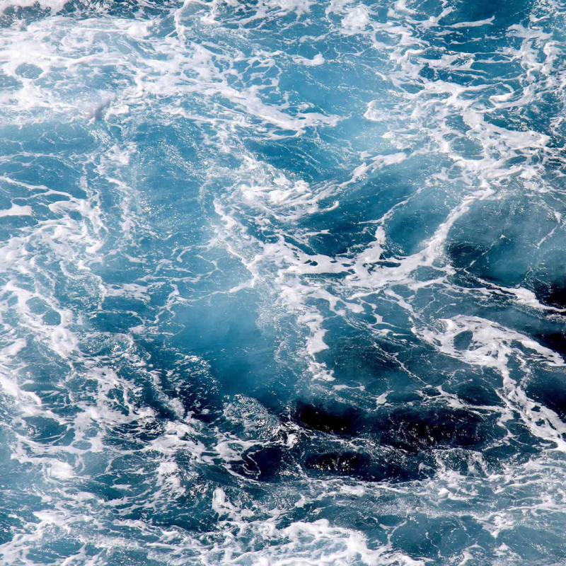 Onde del mare in movimento con schiuma bianca e acqua blu profonda.